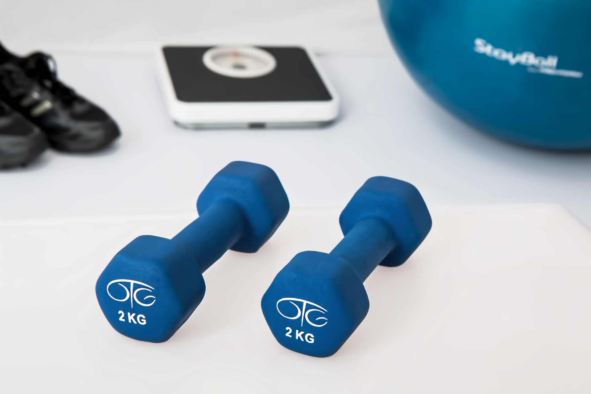 Blaue Hanteln, Waage und Gymnastikball als Ausstattung für Prävention und Training