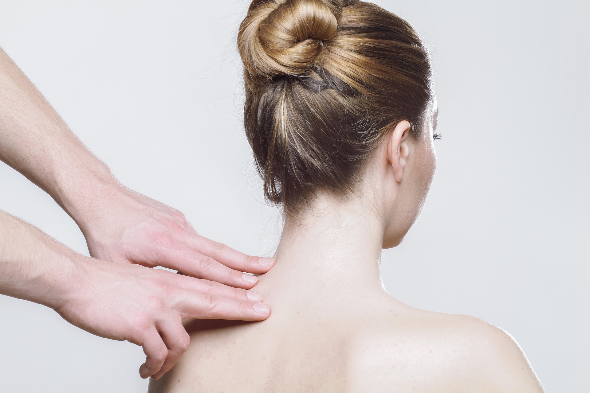 Therapeut behandelt Nacken und Schulter einer Patientin, Bild aus dem Behandlungsalltag